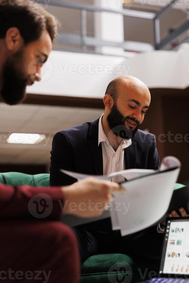 Business people forging connections at international conference, marking a pivotal moment in the business trip. Colleagues sharing new ideas in lounge area, ensuring future partnerships. photo