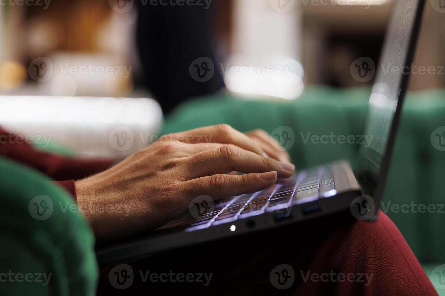 Hotel guest works on laptop at hotel, writing new conference notes to perfect speech before attending international meeting. Businessman in formalwear in lounge area. Close up. photo