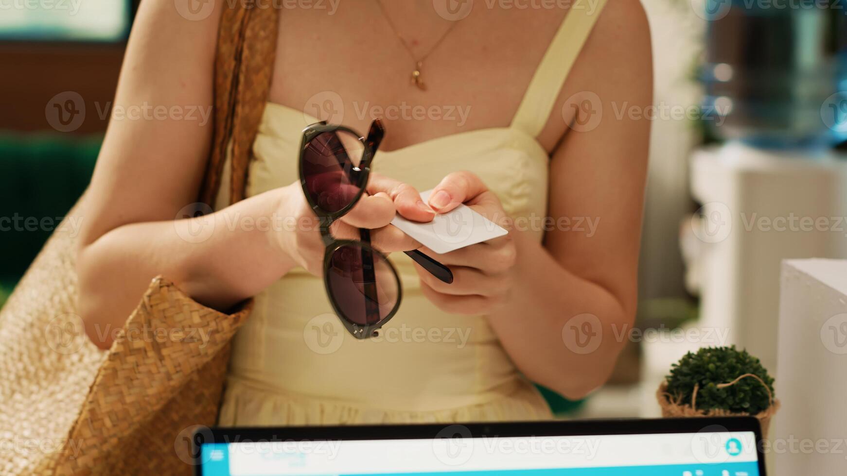 Woman traveller having room access key from reception after doing check in procedure, talking to receptionist about summer holiday. Tourist arriving at hotel resort. Handheld shot. Close up. photo
