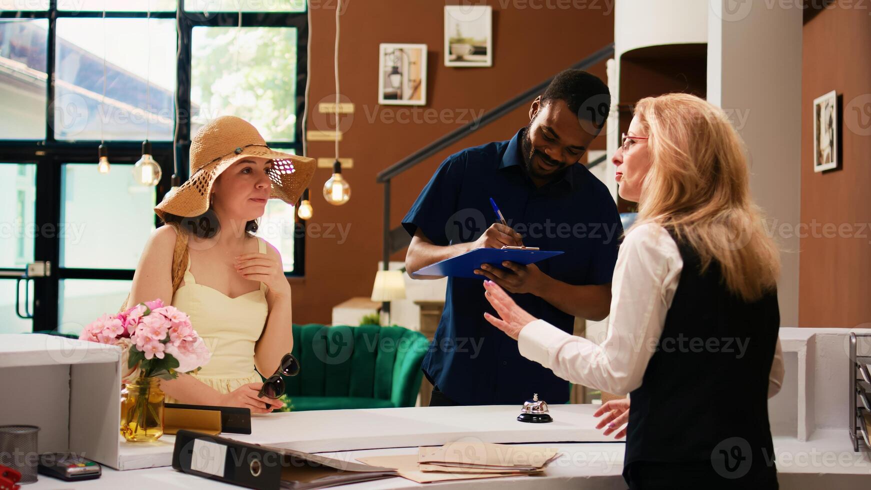 Guests filling in registration papers at reception, doing check in procedure with front desk staff at tropical hotel. Travellers on honeymoon registering at luxury resort. Handheld shot. photo