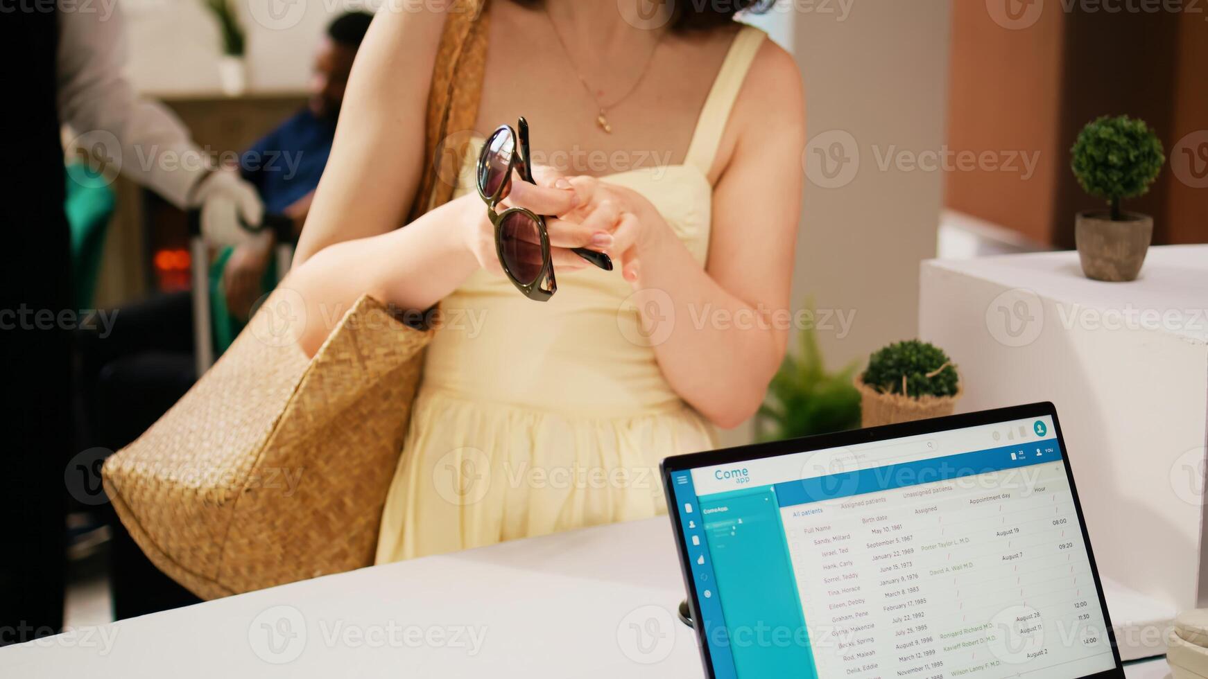 Woman tourist asking for room key card at reception front desk, registering in tropical resort lobby. Traveller dressed in summer clothes having reservation for holiday trip. Handheld shot. Close up. photo