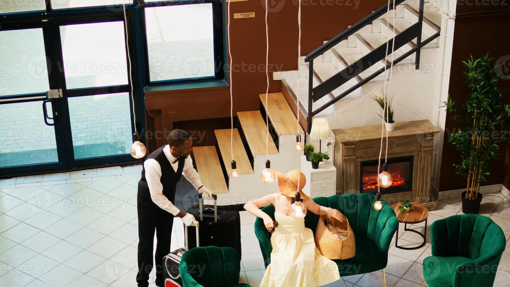 Hotel concierge carrying baggage for tourist, helping with trolley bags in reception lobby. Bellboy working in luxury tropical resort to give assistance to guests, summertime holiday. photo