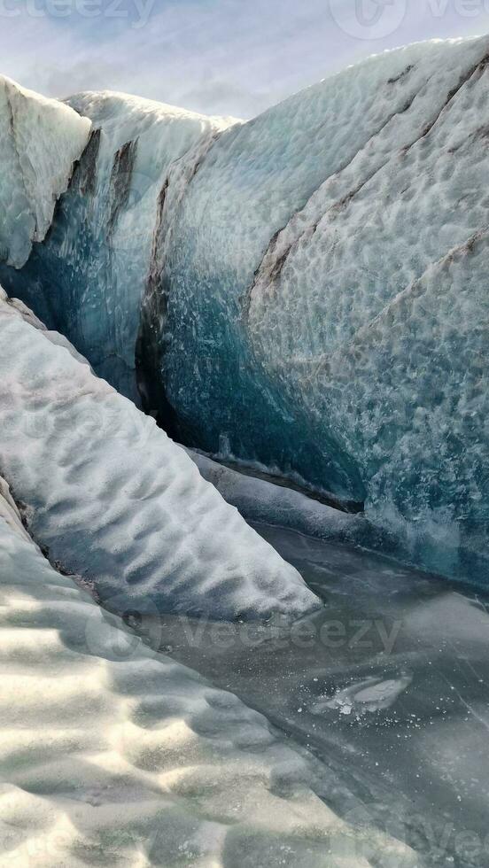 Vatnajokull glacier ice mass in nordic region, spectacular ice rocks with large caves around snowy mountain chain. Majestic frozen icebergs fragments floating on lake, scenic route. photo