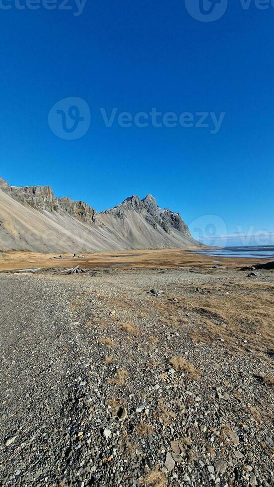 Stokksnes beach features picturesque Vestrahorn mountain range in breathtaking freezing cold natural scenery. Landscape of scandinavian coastline with steep edges and icelandic seas. photo