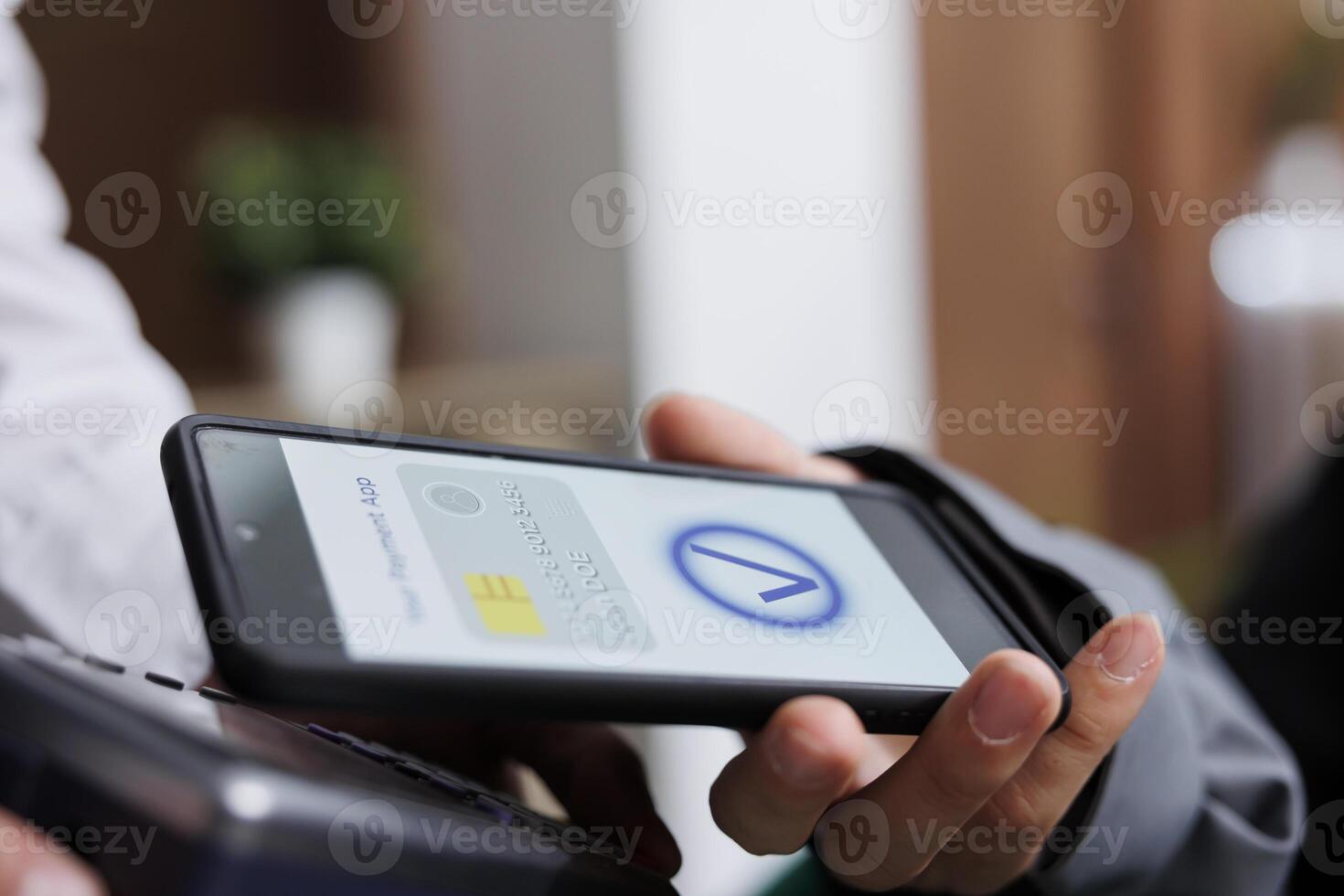 Close-up shot of tourist making contactless payment via mobile phone using NFC technology. Detailed view of pair of hands grasping pos terminal and smartphone, paying winter holiday reservation. photo