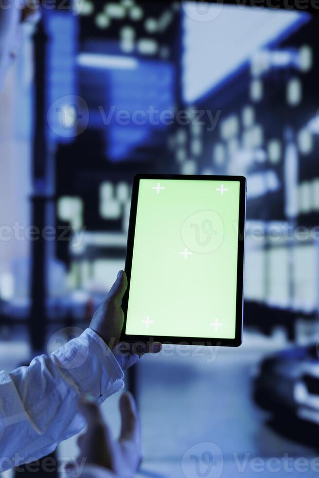 Person having fun walking around city at night, scrolling on social media using mockup tablet, close up. Citizen using green screen device while strolling in empty metropolitan setting photo