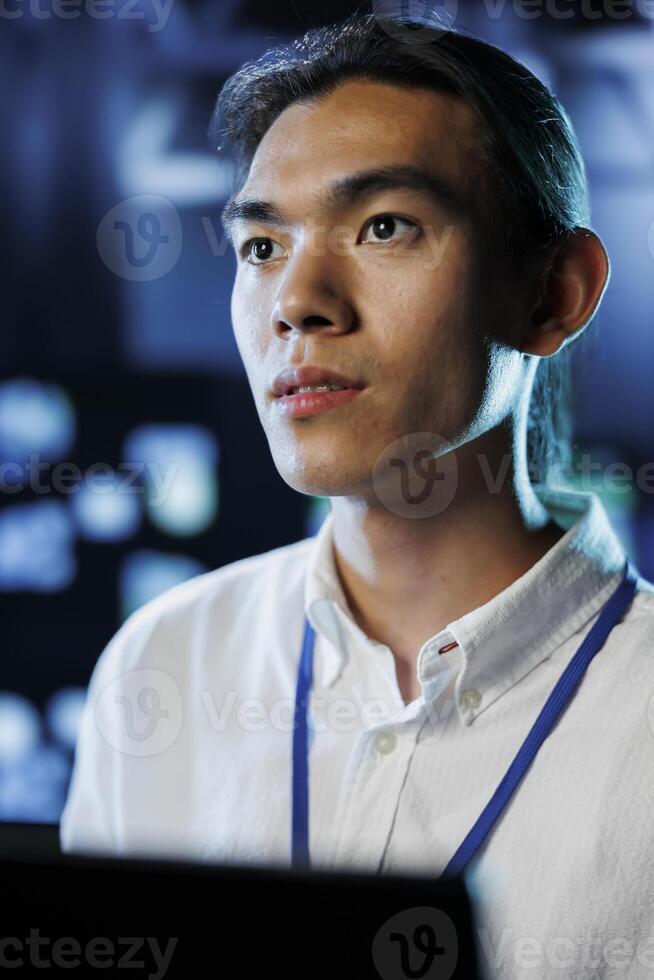 Portrait of technician between server hub clusters providing processing resources for businesses worldwide. Experienced professional fixes data center mainframes tasked with managing massive databases photo