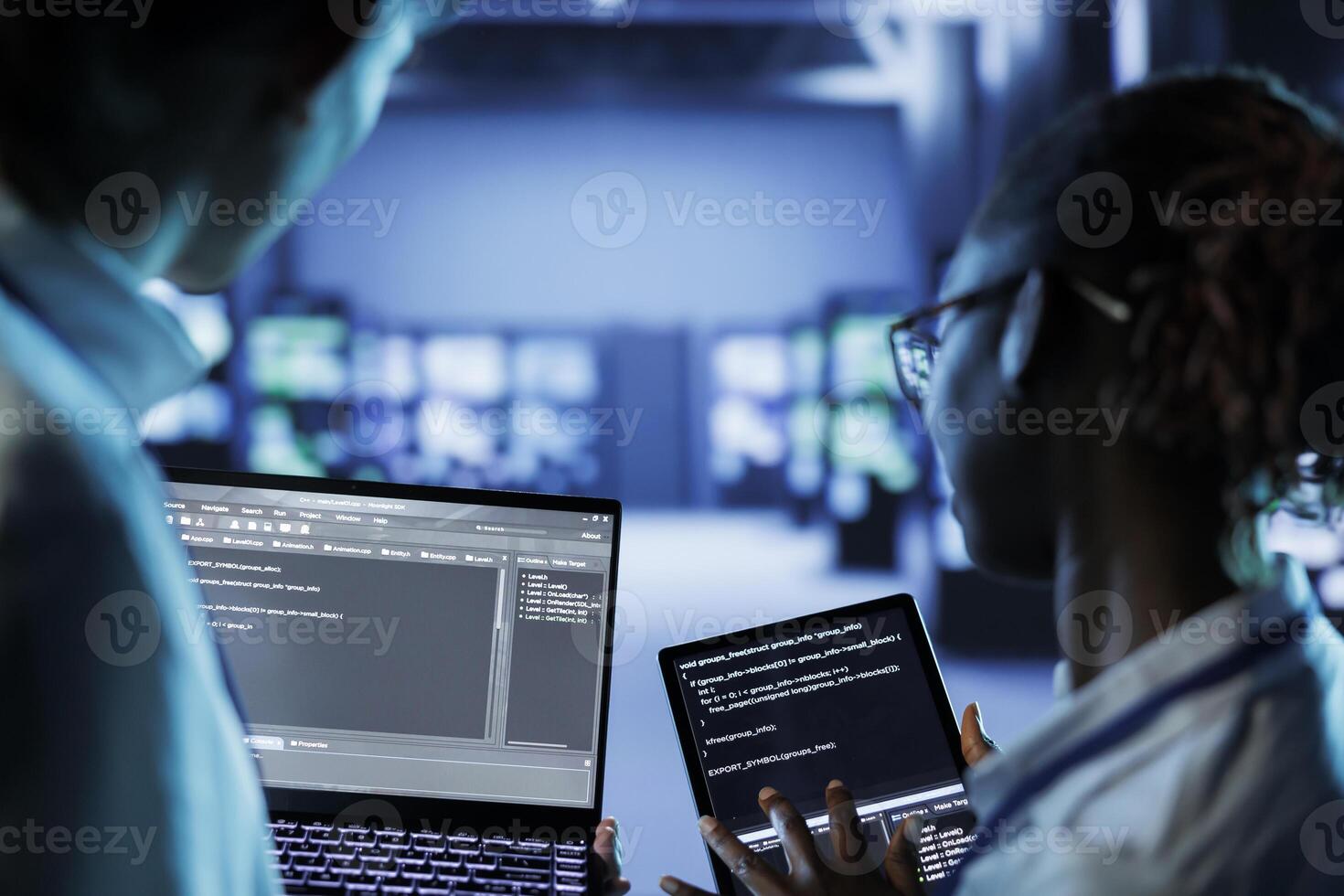 IT developers building firewall systems in server room housing advanced infrastructure. Licensed specialists running code on tablet and laptop, to upgrade data center rigs handling demanding workloads photo