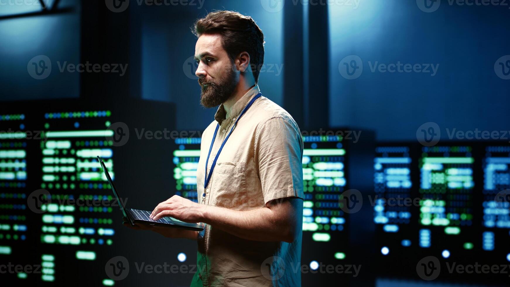 Programmer doing annual system examination, checking data on laptop of needed debugging in server mainframes housing advanced data storage hardware supporting important IT workloads photo