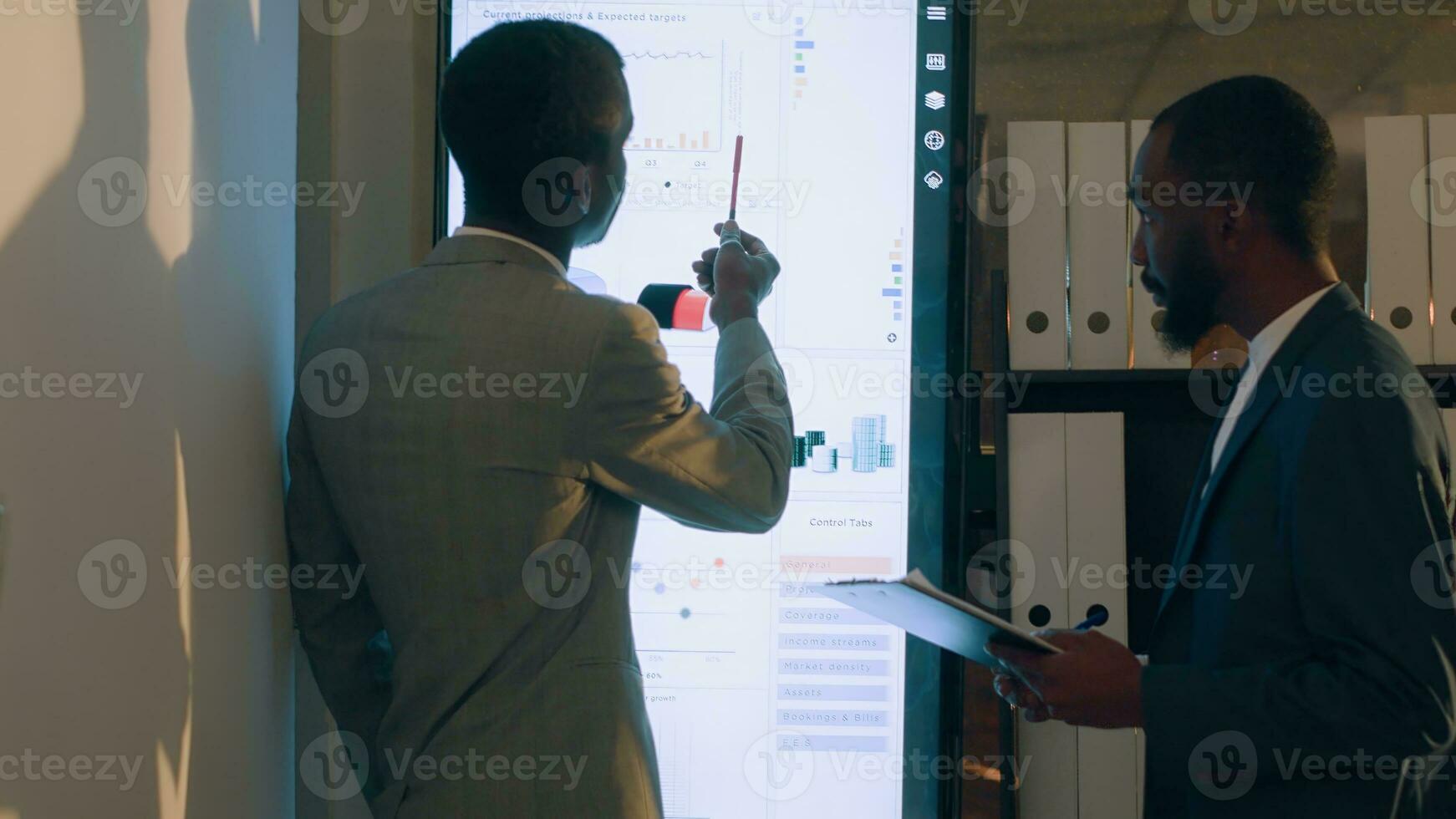 Supervisor showing employee useful datasets on digital screen to help him finish project tasks. Business executives looking over accounting figures in office during nightshift photo