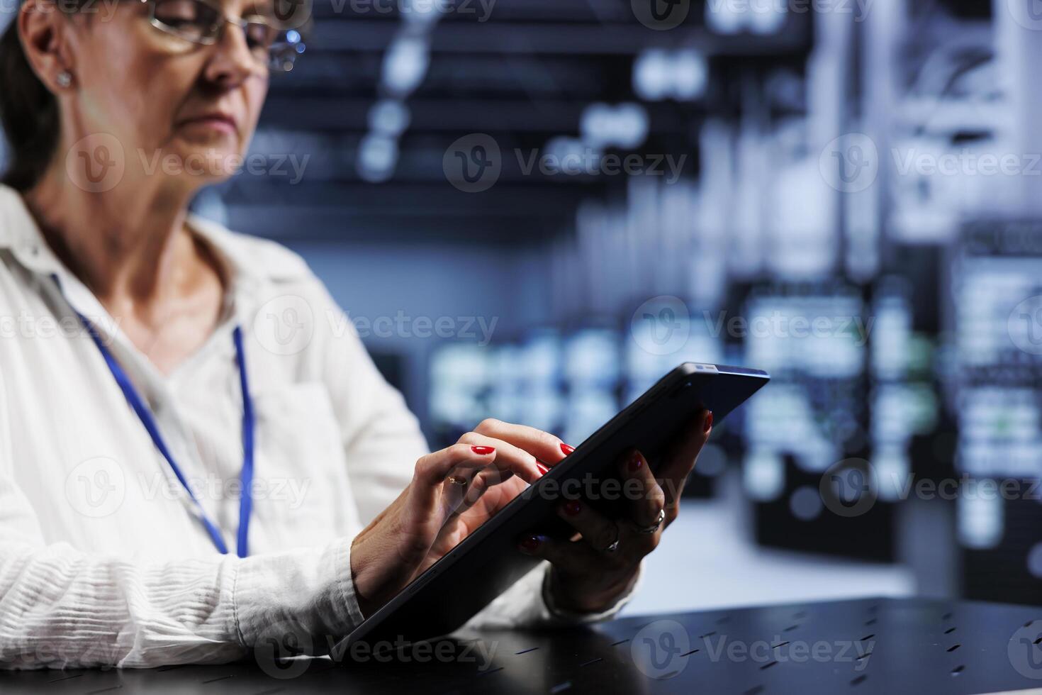 Aged technical support consultant using tablet to assess server security glitches arising due to unsecured network connections. Certified expert ensuring data center is impenetrable by virus attacks photo