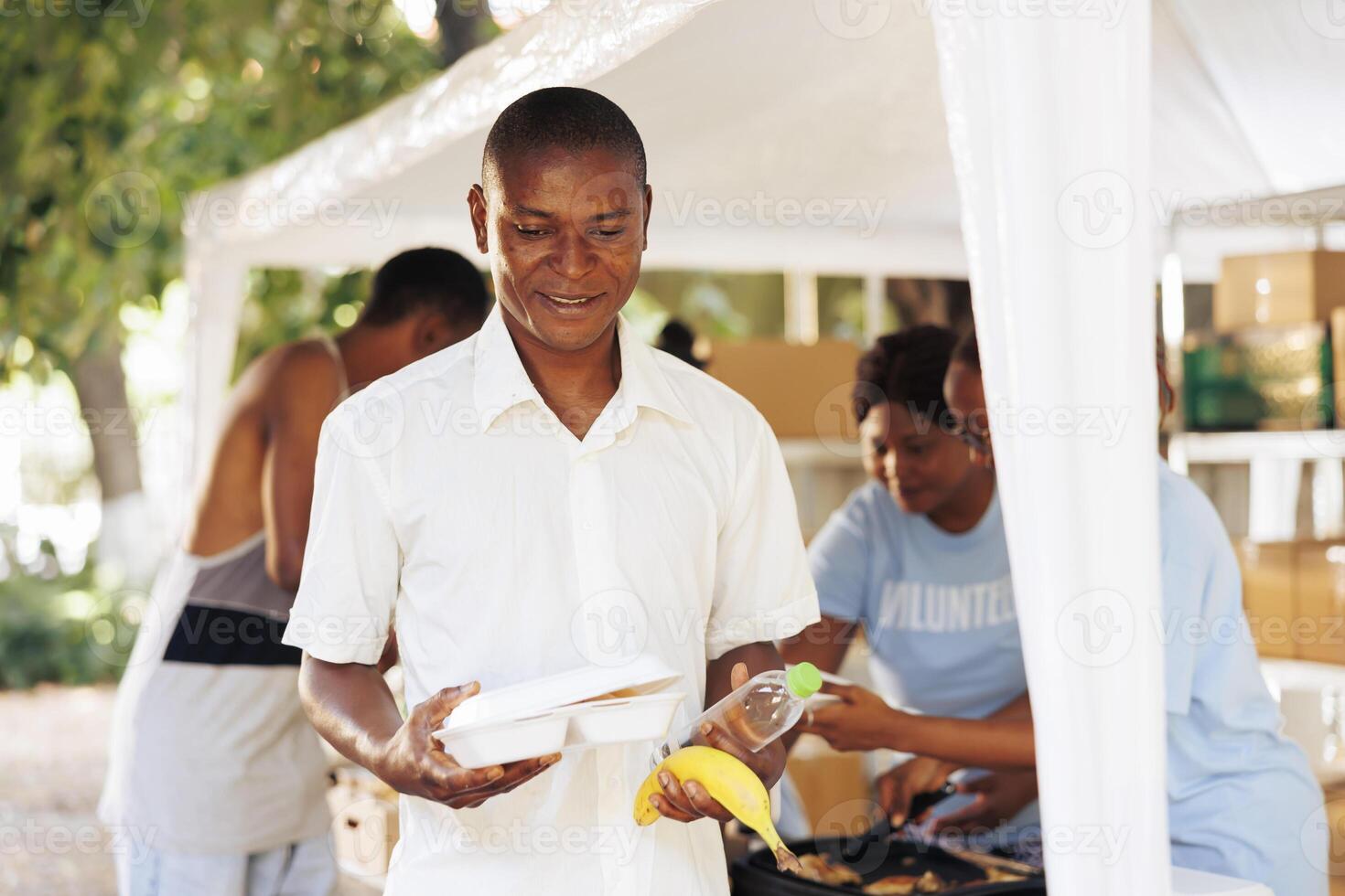 Multiracial hunger relief organization operating outside to provide homeless people with free meals and necessities. Nonprofit group help the needy and the less fortunate with fruits and warm food. photo