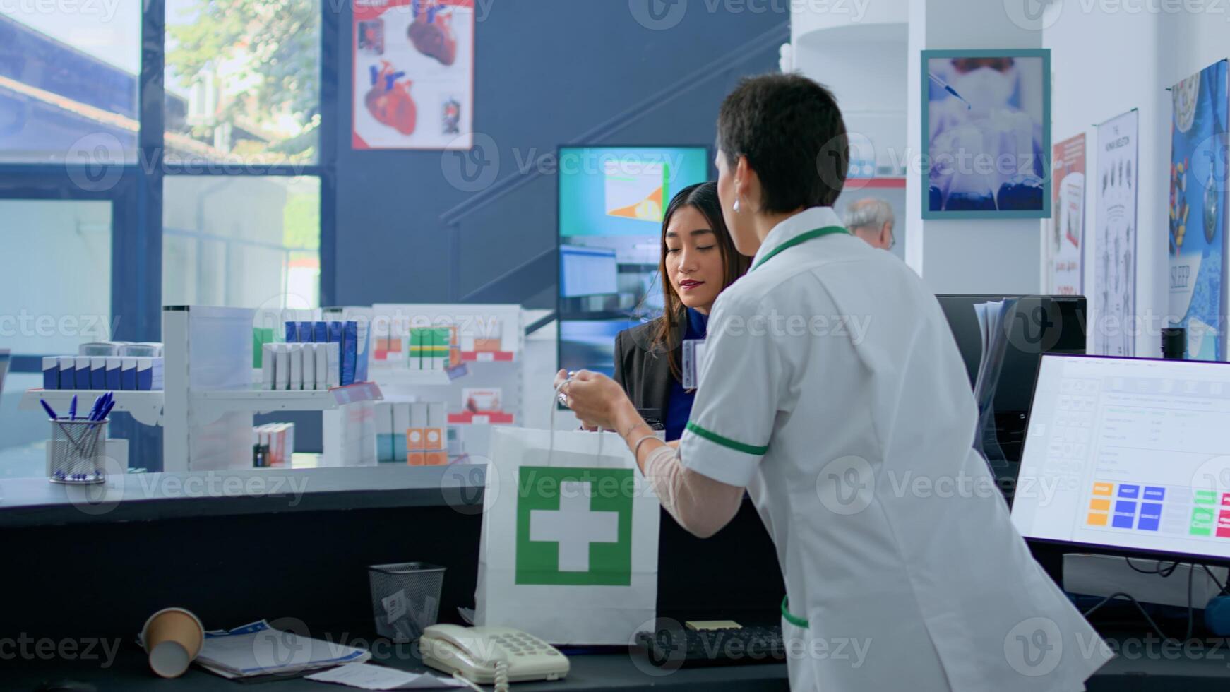 Client in drugstore at checkout counter using credit card to purchase medical items, being help by pharmacist with bagging process. Customer doing contactless paying in apothecary photo