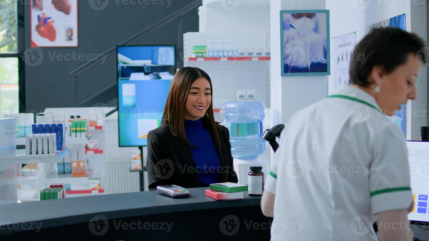Elderly pharmacy assistant helping asian client pick ideal medicinal products for ailments relievement before reaching drugstore counter. Shopper purchasing supplements and vitamins photo