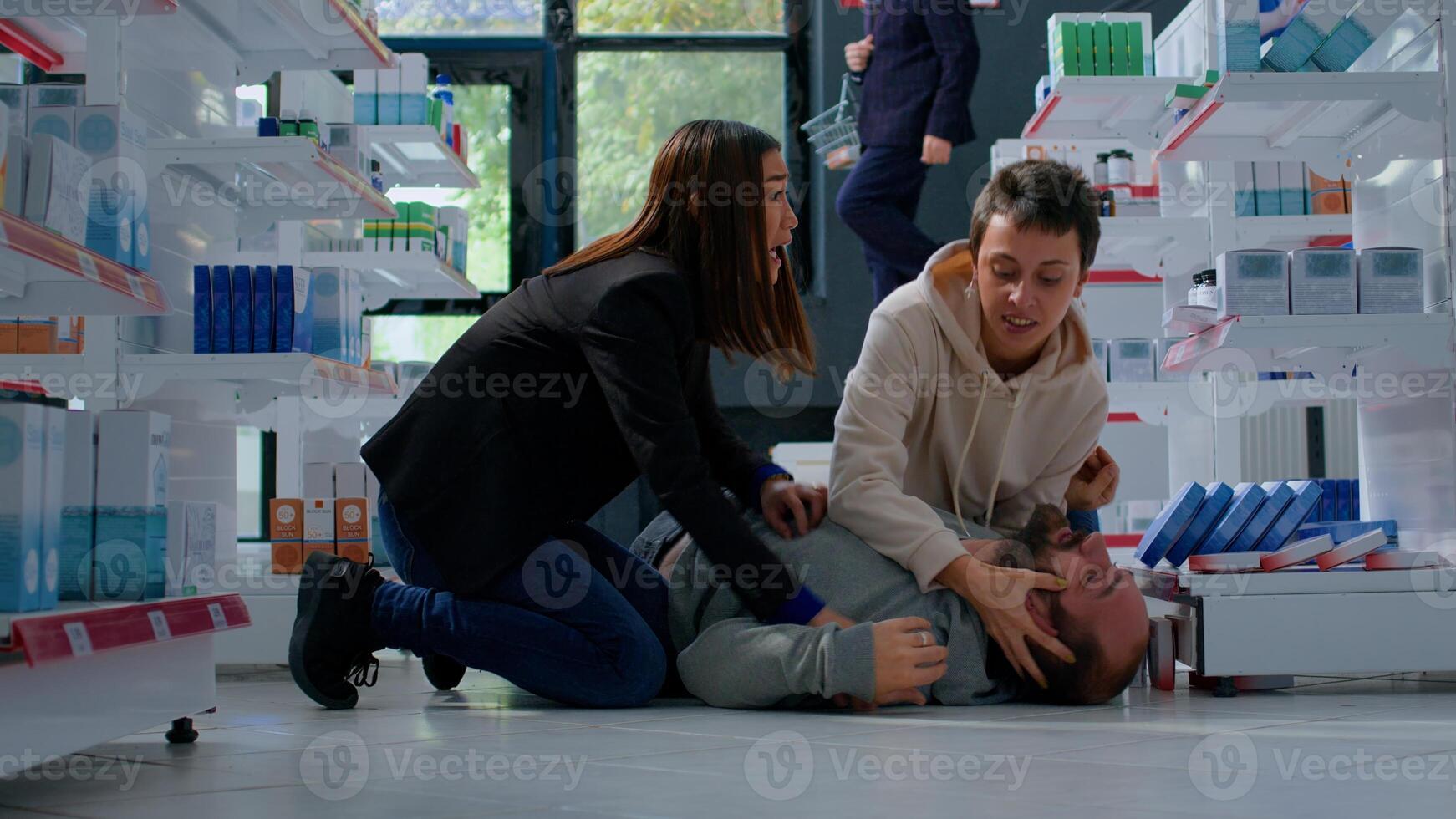 Man strolling through pharmacy getting sudden epilepsy attack, fainting and requiring medical help. Panicked customers trying to save convulsions suffering victim twitching on floor photo