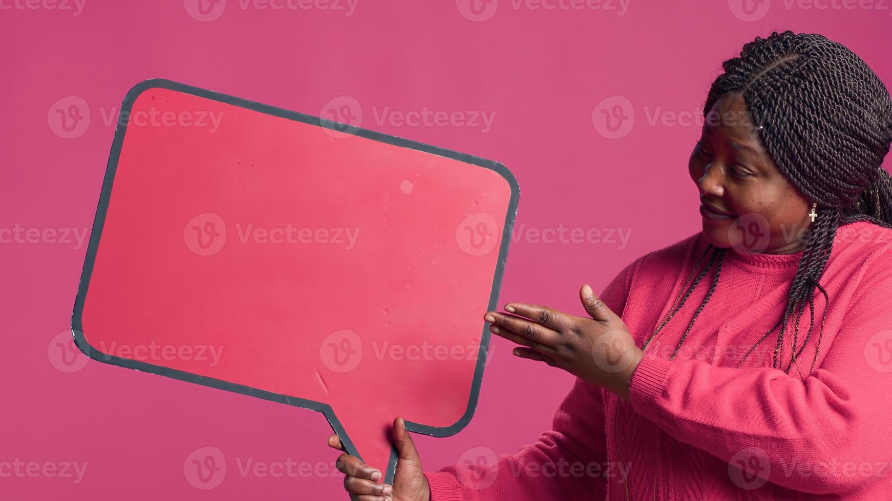 African American beauty holding a red speech bubble mockup for text messages and notes in her right hand. Black lady nodding in agreement with the content of the word-bubble copyspace template. photo