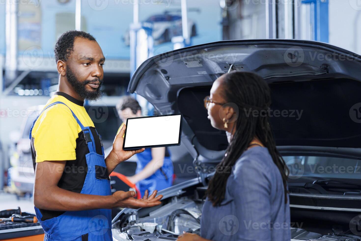 Qualified serviceman in car service uses mockup tablet to order new exhaust pipes for broken vehicle. BIPOC garage specialist shows client needed components replacement on isolated screen device photo