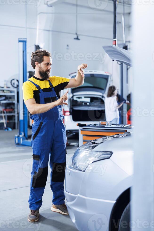 Serviceman in repair shop using augmented reality holograms to check car condition during maintenance. Garage employee using futuristic AR technology to examine out of order vehicle photo