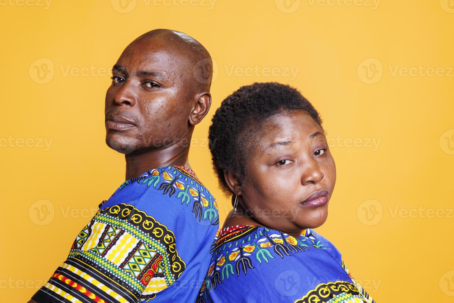 Serious black man and woman standing back to back closeup portrait. African american man and woman looking at camera with serious expression while posing together in studio photo