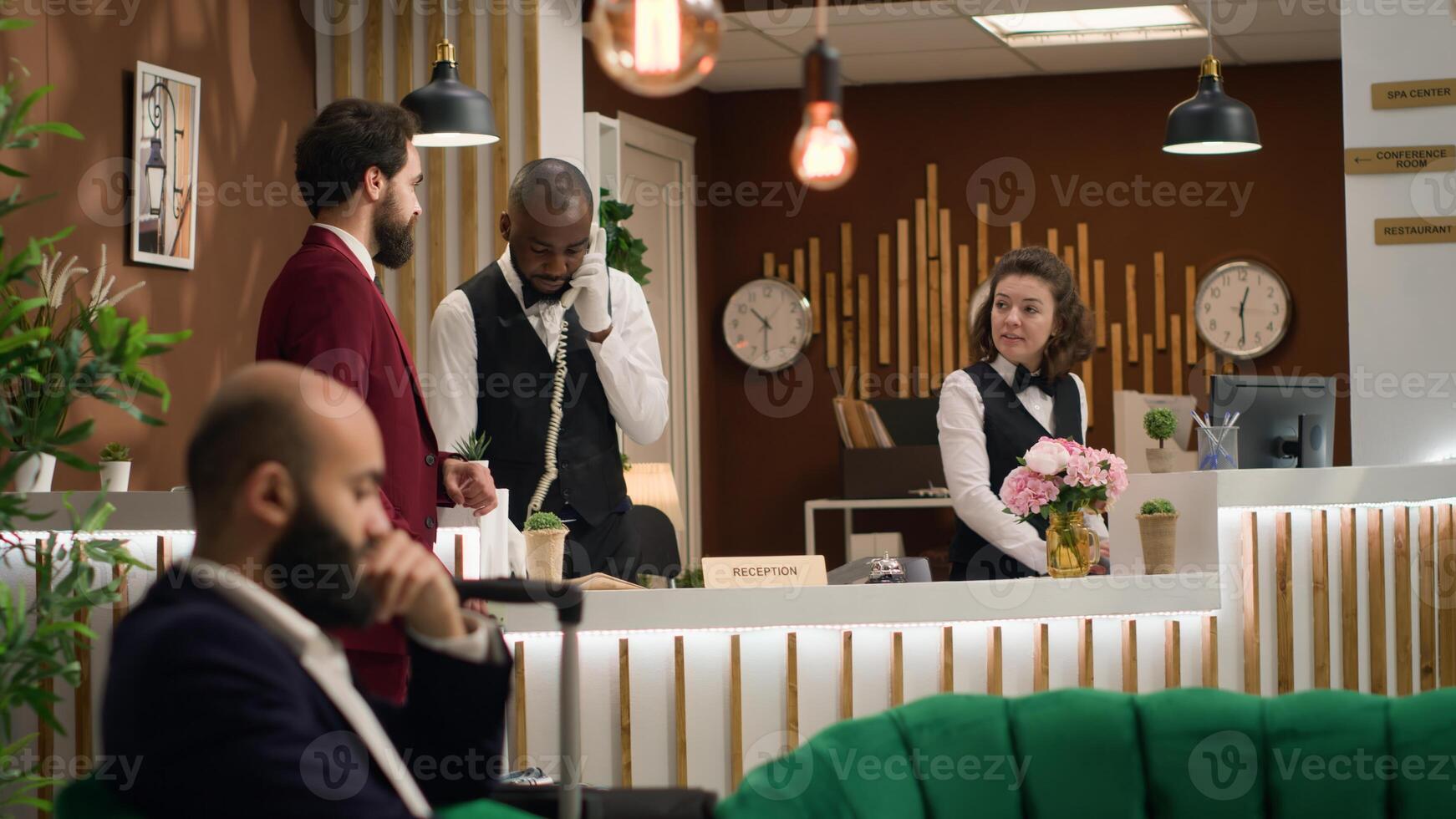 Businessman asks for front desk services, talking to hotel concierge personnel about facilities while he travels for work. Entrepreneur in suit arriving at reception for check in process. photo