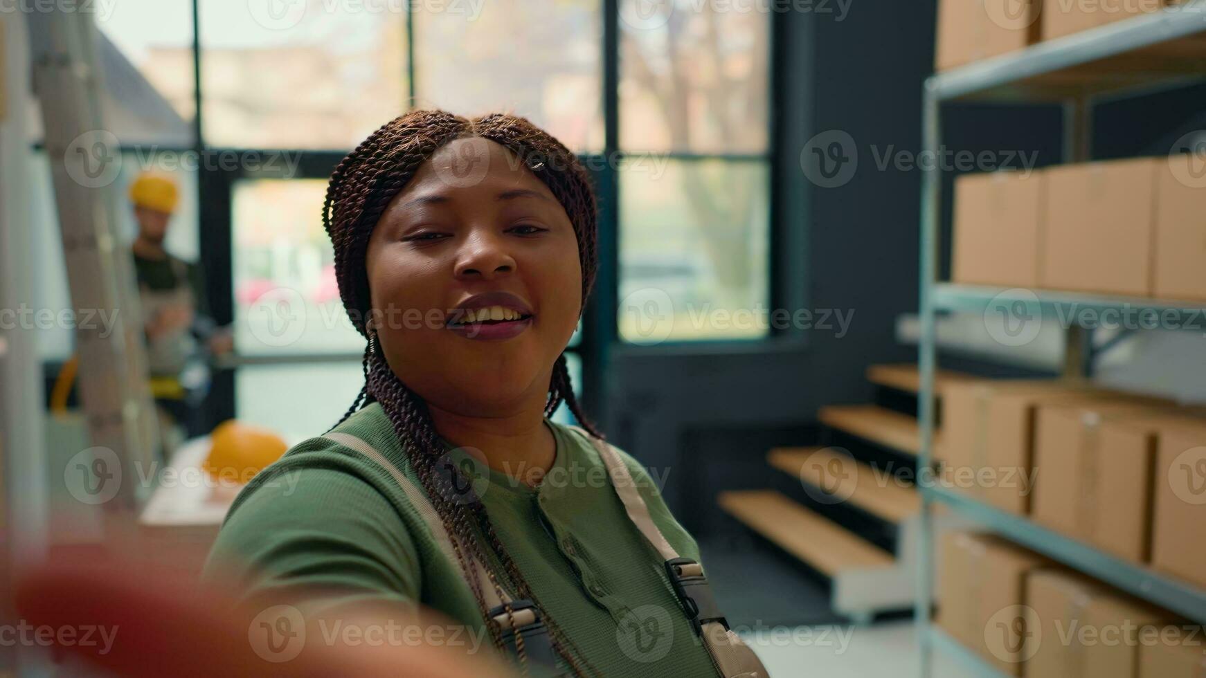 African american warehouse head of logistics using selfie smartphone camera, filming introduction video for new interns starting job in storage facility, teaching them safety measures photo