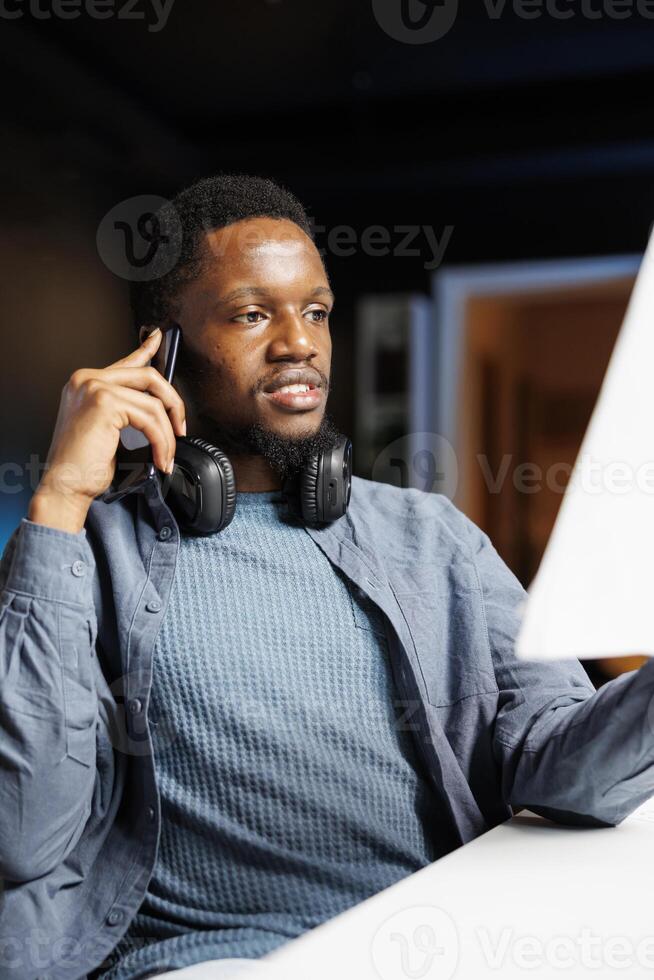 At home, investment banker studies equity balance statement sheets while engaged in remote tasks and discussing on call with director. Analyst uses revenue tracking records to boost profit. photo