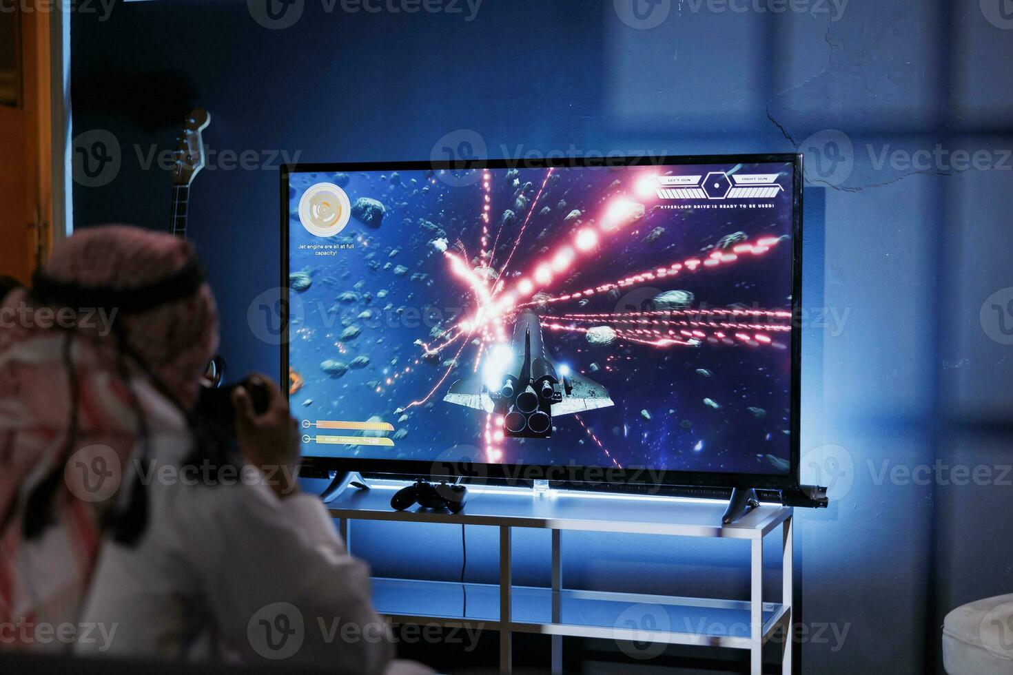 A Middle Eastern man playing a digital game at home. Immersed in cyberspace, he controls the game with a joystick, sitting in front of a detailed television screen. photo