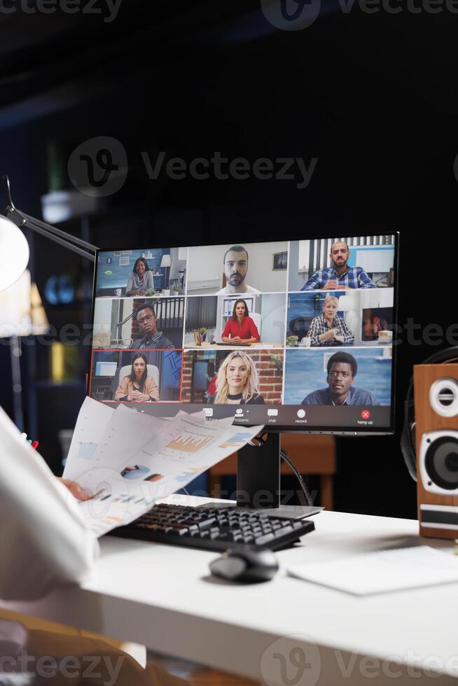 Selective focus on the desktop screen displaying group of people participating in a video conference. Detailed image of professional adults discussing their research in an online meeting. photo