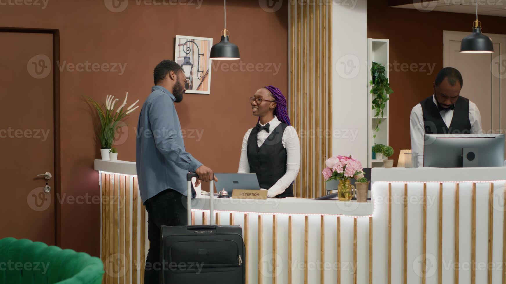 Person does check in at reception, entering five star hotel and signing registration forms at front desk. Hotel concierge worker welcoming tourist at resort, providing great services. photo