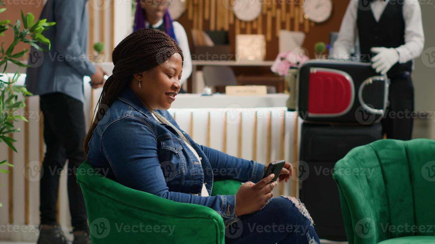Tourist browsing online page on phone as she sits in lounge area at hotel, using smartphone app to read social media texts. African american woman travelling on vacation. Handheld shot. photo