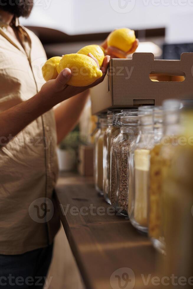 Client purchasing nutritious lemons grown by zero waste supermarket owner in his garden. Vegan customer happy to find eco friendly additives free fresh fruits in local store, close up photo