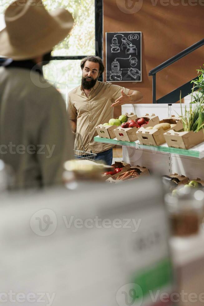 Male customer gestures curiously while holding a basket in an environmentally friendly grocery store. Caucasian man looking around supermarket for freshly harvested organic produce. photo