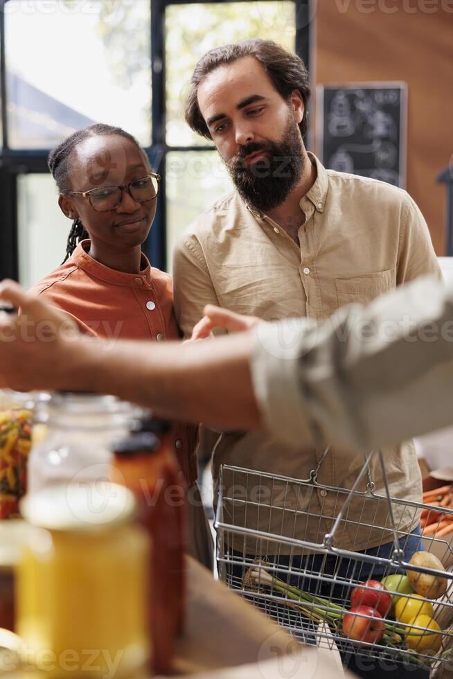 Close-up of caucasian boyfriend and African American girlfriend browsing through a section filled with fresh and natural merchandise. Interracial couple with a basket doing organic food shopping. photo