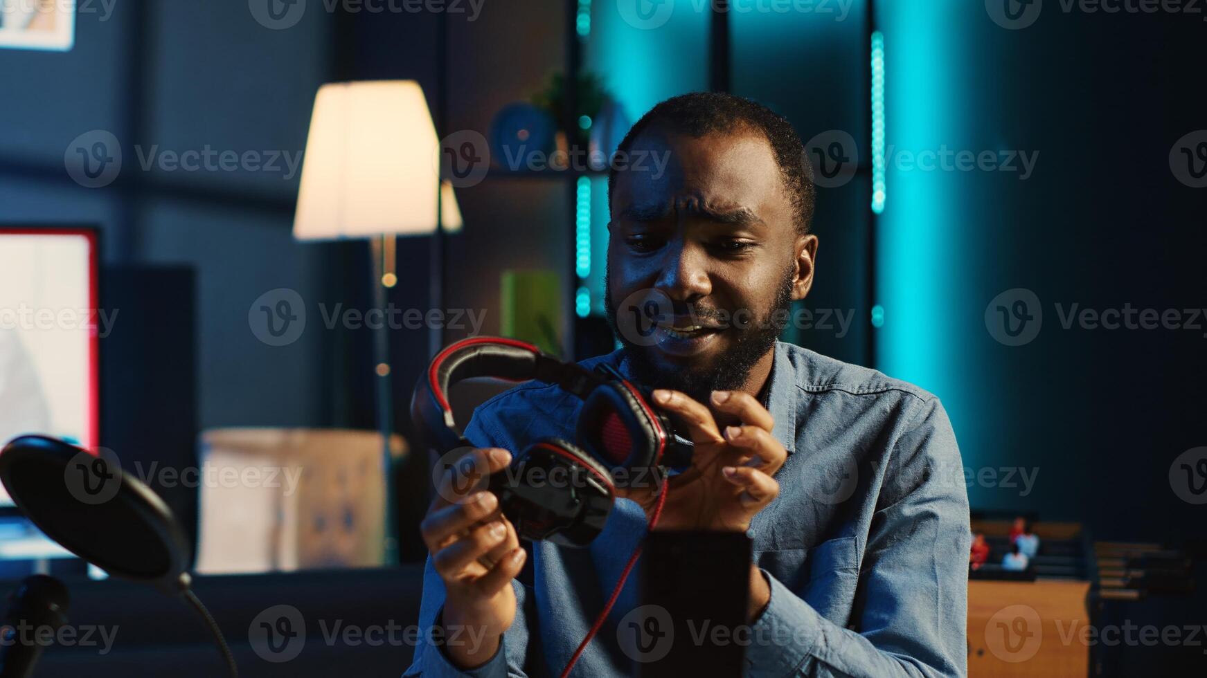 African american technology internet star filming review of newly released RGB lit keyboard, mouse and headphones, giving audience feedback about gaming capabilities, doing endorsement photo