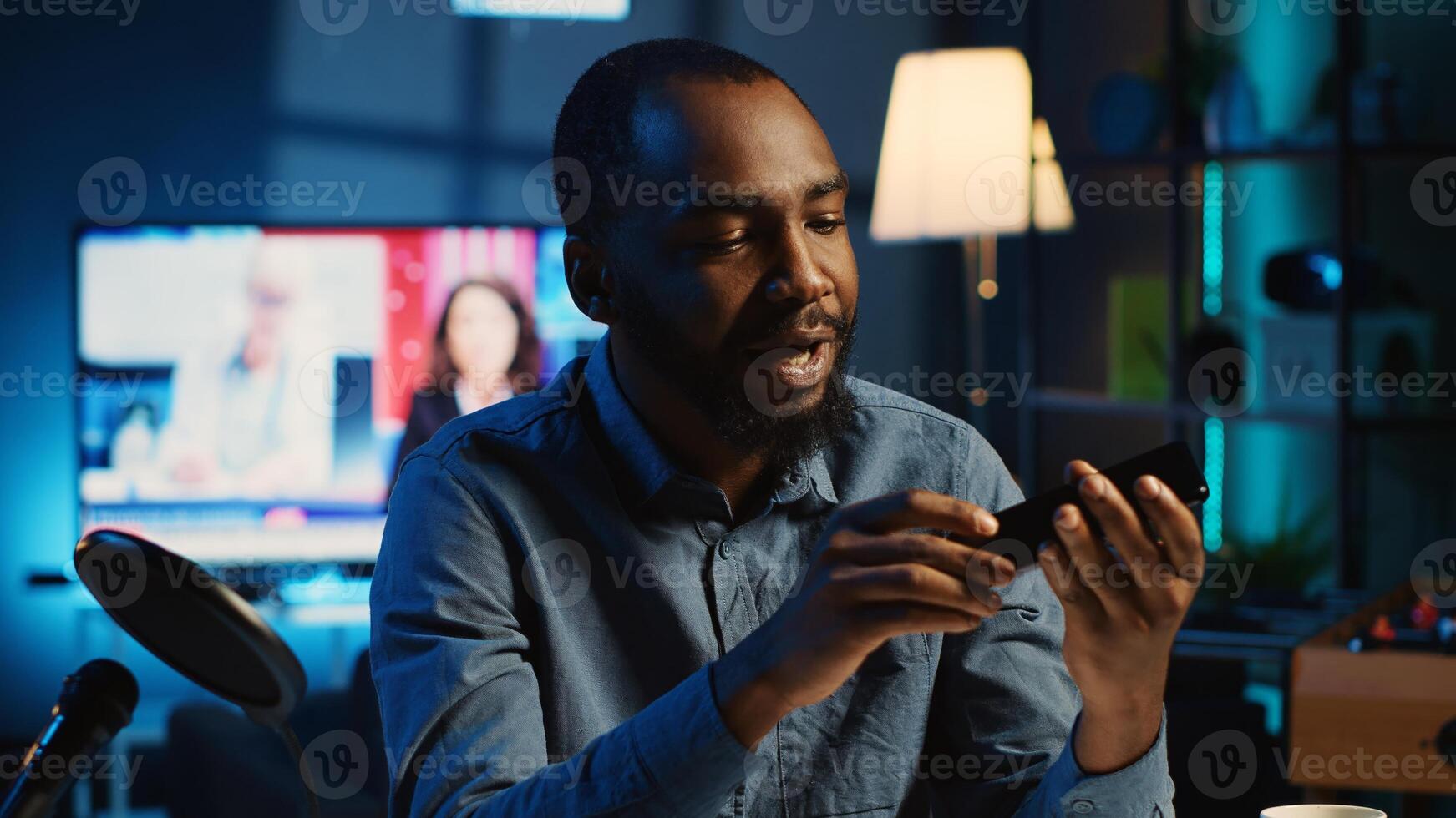 BIPOC tech content creator filming technology review of newly released smartphone, unpacking it and presenting specifications to audience. Influencer showing phone recommendation to subscribers photo