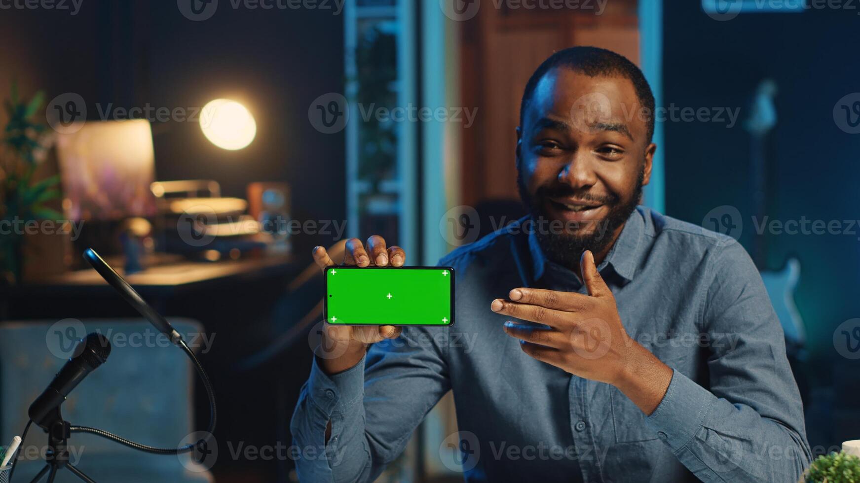 Content creator in studio films newly released green screen smartphone video review for tech enthusiasts. Viral online star hosts technology internet show, unboxing mockup cellphone photo