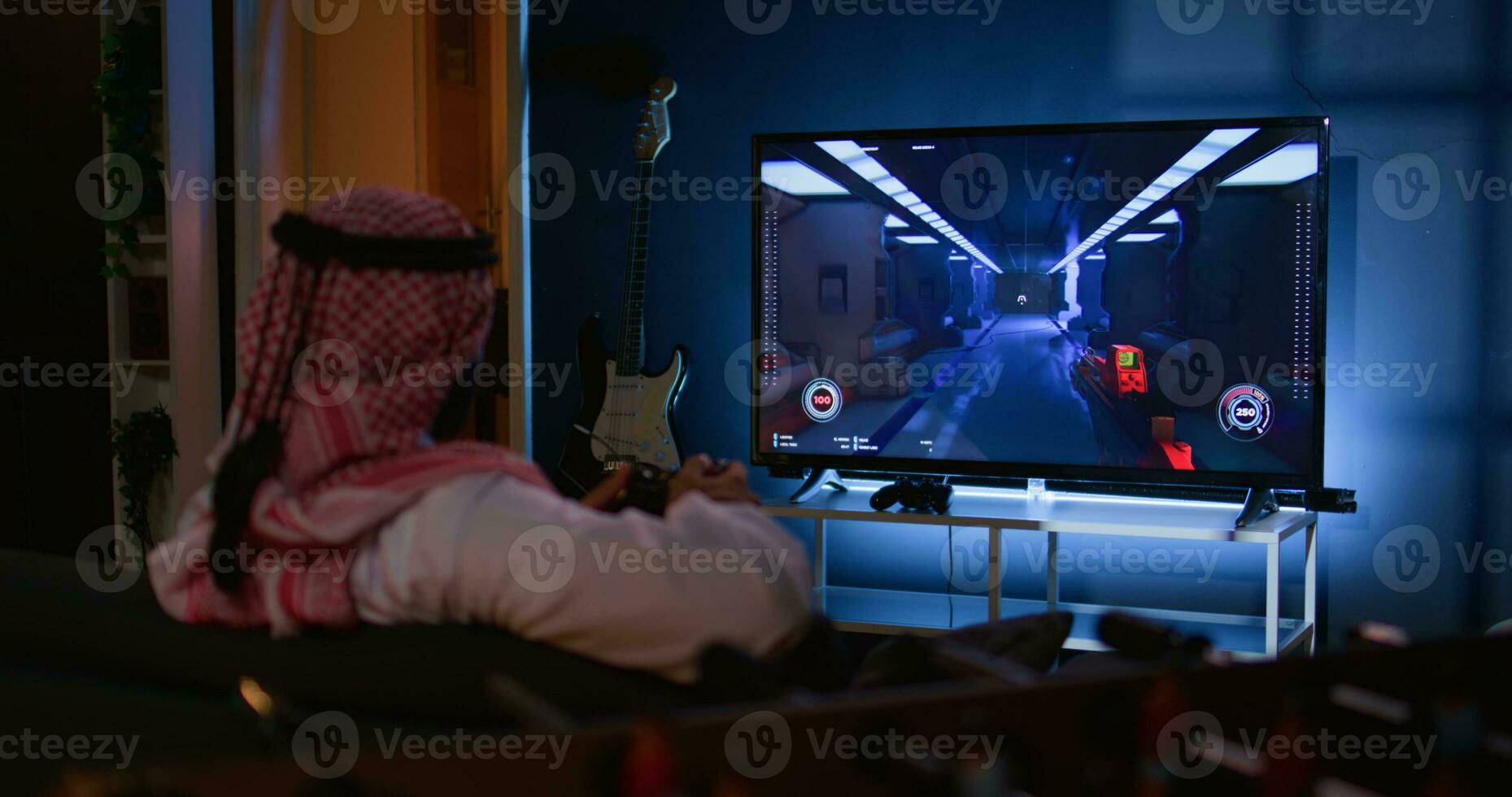 Arabic man playing singleplayer videogames on TV, relaxing after long day at work. Middle Eastern gamer enjoying science fiction shooter game on gaming console, having fun photo