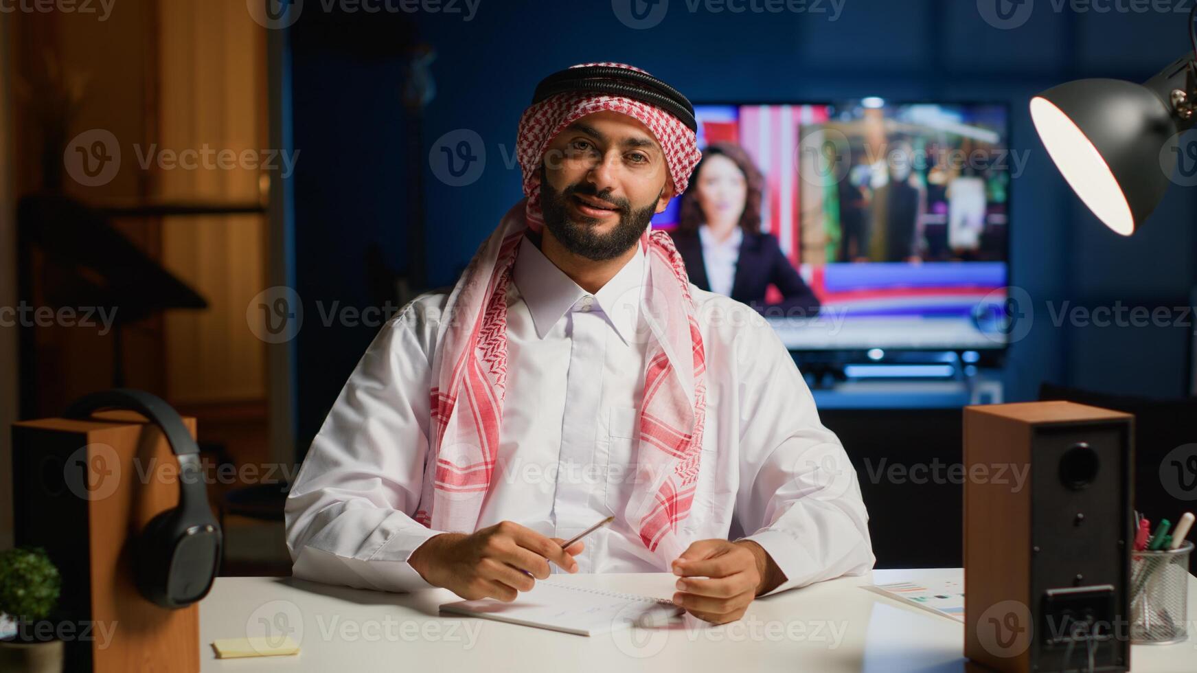 Portrait of smiling arab man engaged in elearning webinar video conference with teacher. Middle Eastern student in online videocall greeting tutor, paying attention to his words and taking notes photo