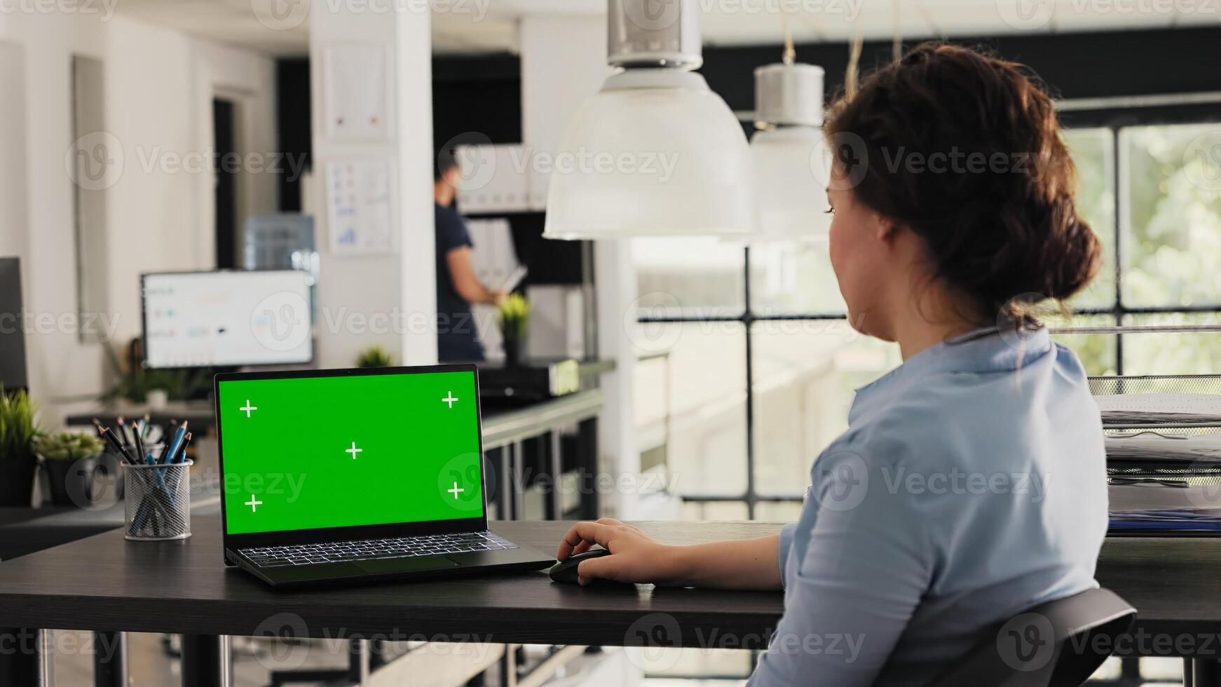 Manager working with greenscreen on laptop, checking isolated mockup template in creative agency office. Young adult looking at pc showing blank chromakey layout on display, modern software. photo