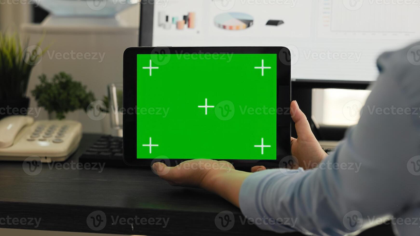 Woman checking greenscreen on tablet in creative agency coworking space, looking at chromakey display with isolated mockup on mobile gadget layout. Employee holding mockup device. photo