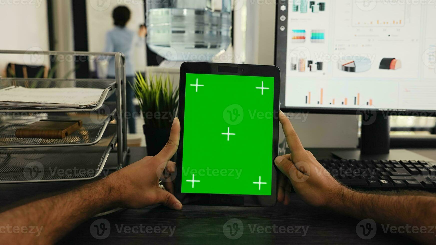 POV of businessman holding tablet with greenscreen template, looking at chromakey display and sitting coworking space desk. Person examining isolated mockup copyspace on gadget screen. photo