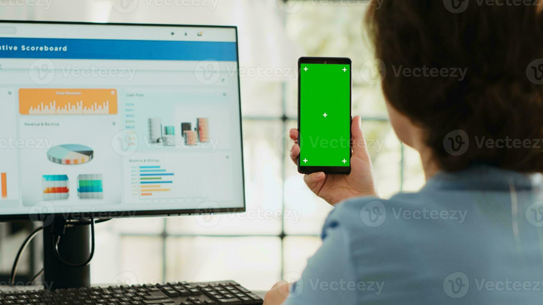 Manager holds phone with greenscreen in business agency workplace. Businesswoman working with isolated mockup template while showing blank chromakey display, startup job tasks. photo