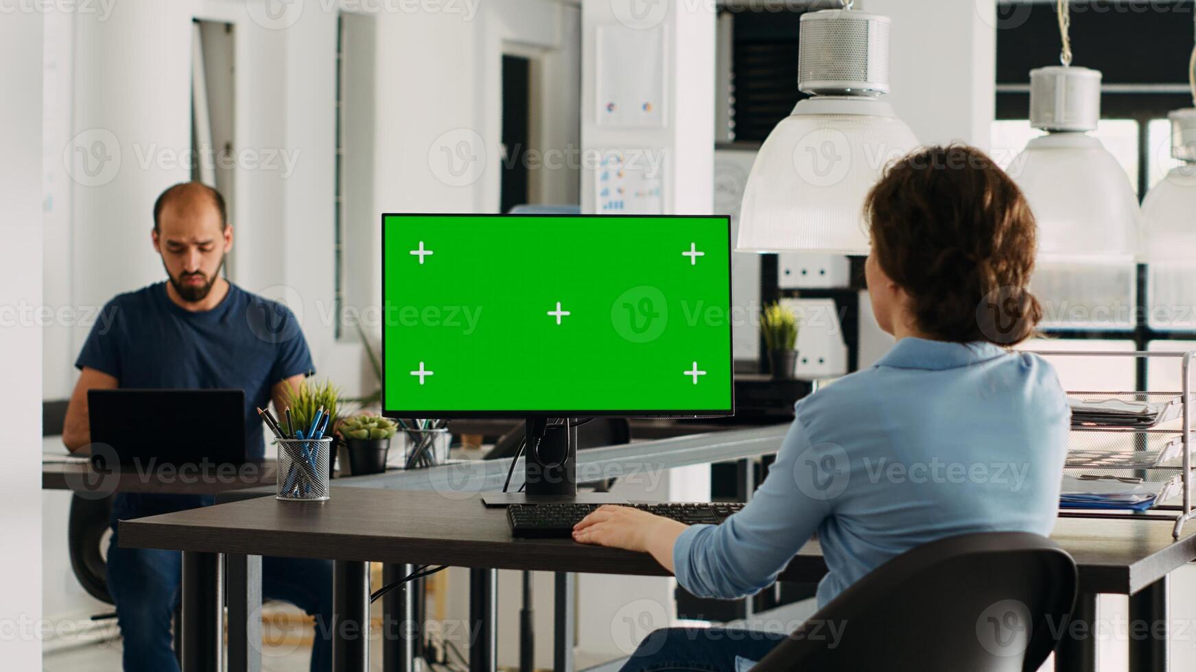 Employee using computer at desk, monitor running greenscreen template in business agency office. Company specialist looking at isolated chromakey display with mockup copyspace, digital network. photo