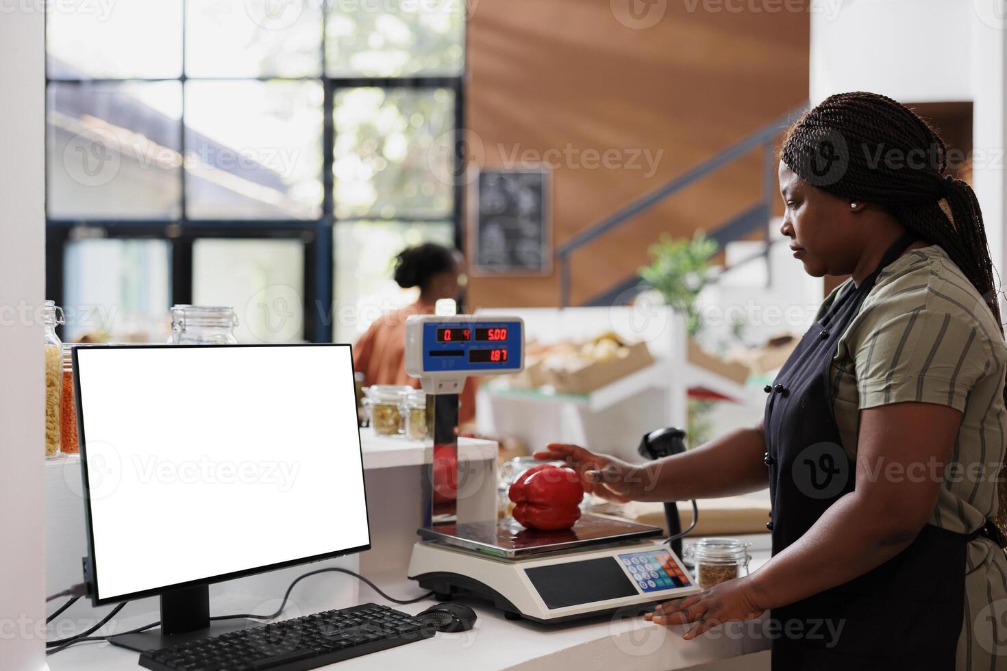 Vendor weighing organic sustainable produce on digital scale while computer displays isolated mockup template for bio food market promotion. Desktop pc at checkout counter showing white screen. photo