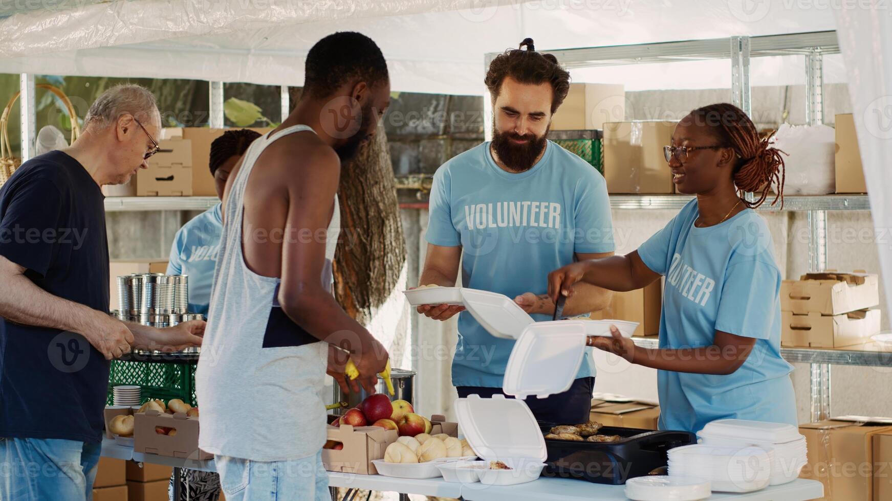 Multicultural volunteers distribute free food and essentials to the underprivileged. Voluntary people provide the less fortunate with humanitarian aid and hunger assistance in homeless shelters. photo