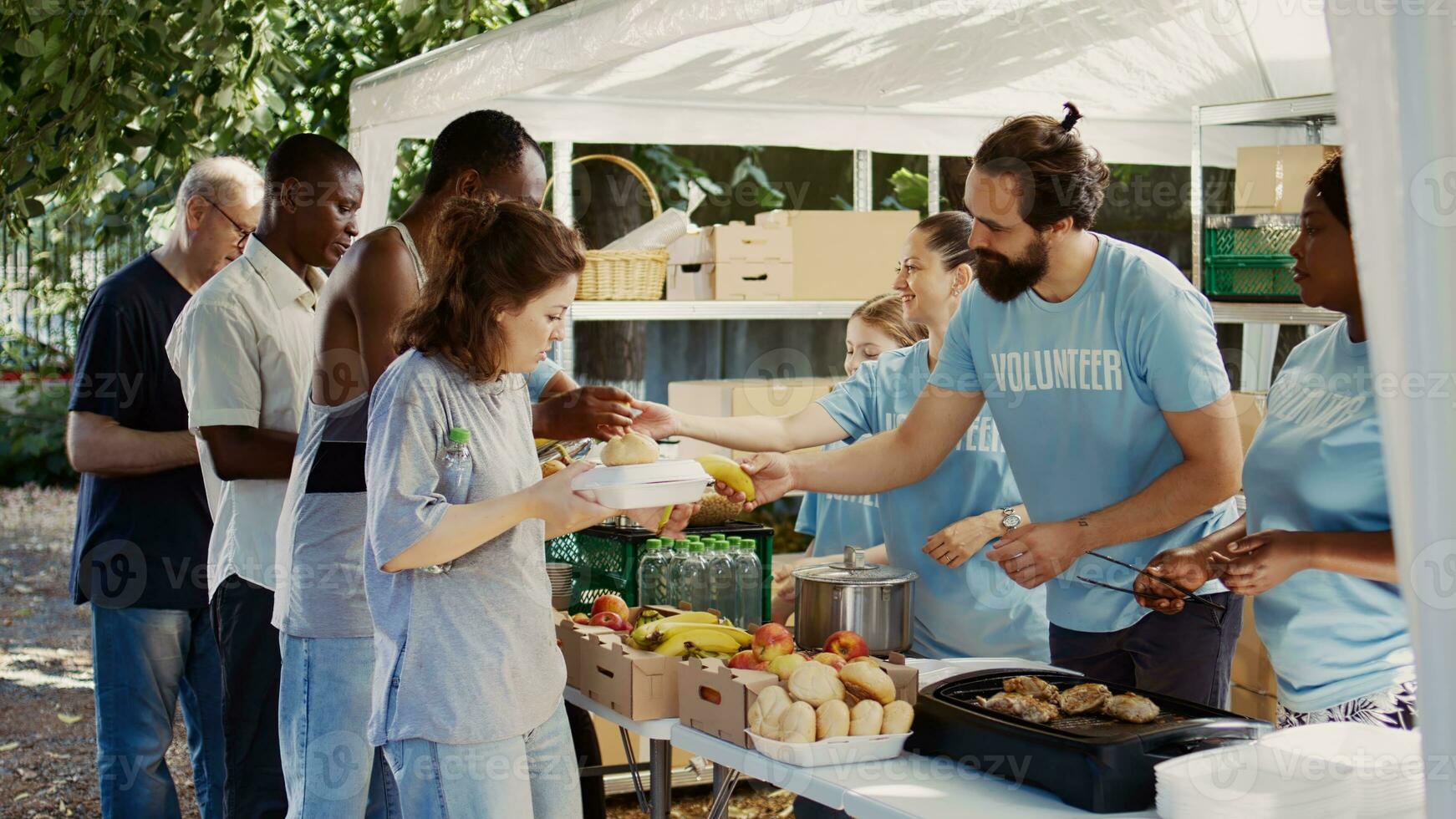 Empathetic volunteers give free meals and humanitarian relief to the needy and less fortunate. Poor and homeless individuals of all races are fed by the non-profit organization at a food drive. photo