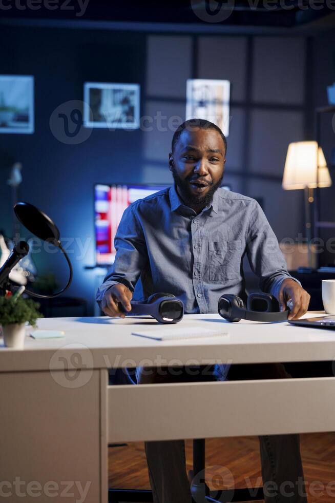 Excited content creator in studio films headphones comparison video review for tech enthusiasts. Trending audio engineer, hosts technology internet show, unboxing music listening devices photo