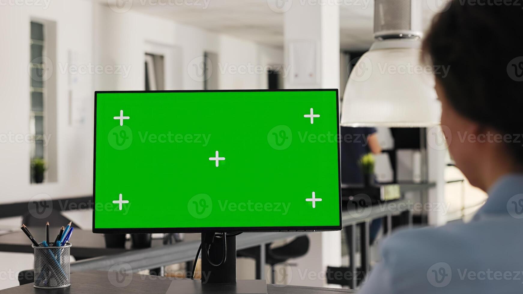 Office manager uses greenscreen on pc and working with isolated monitor display for business development. Woman looking at computer showing blank chromakey layout on desk. Handheld shot. photo
