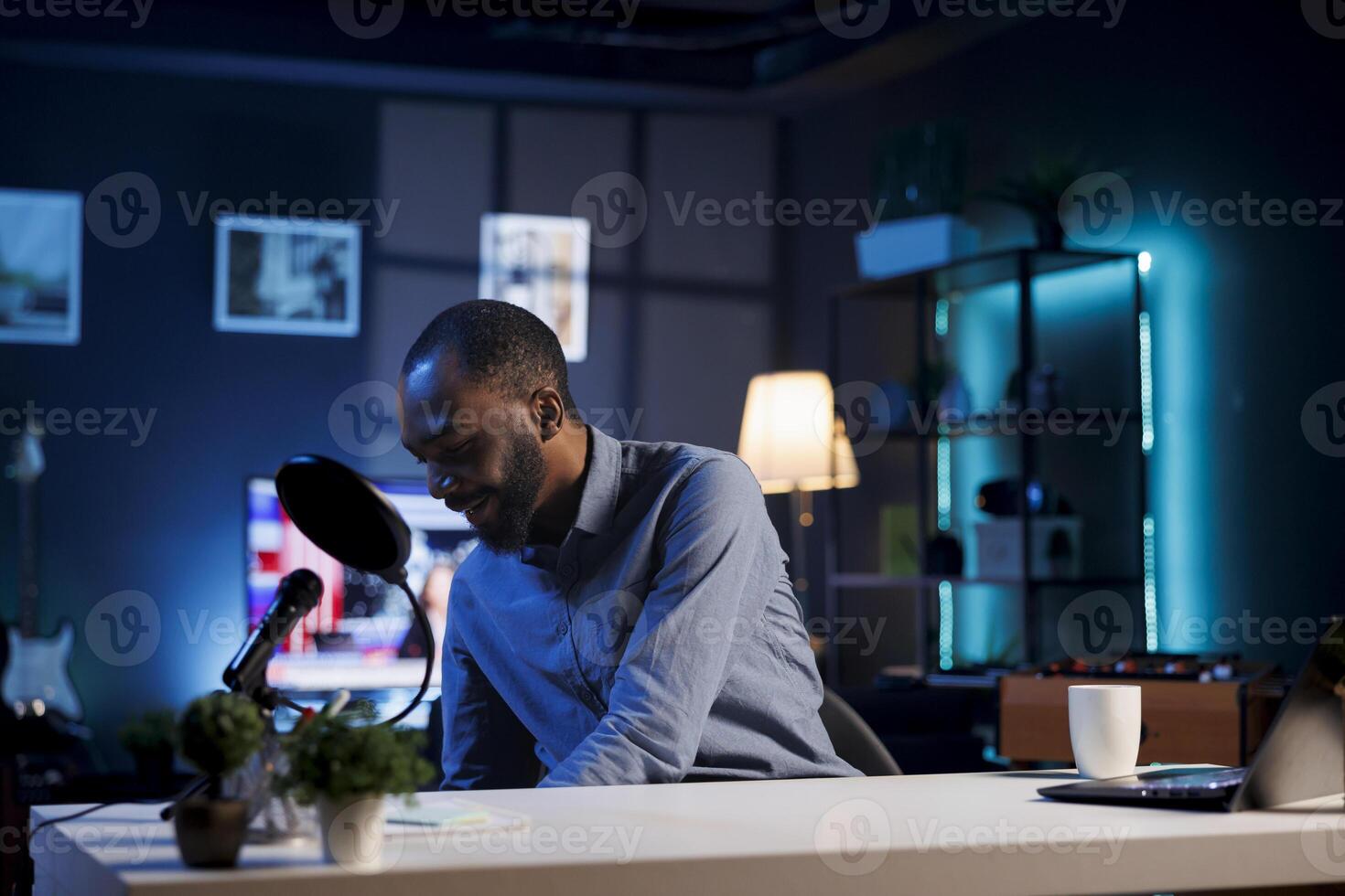African american content creator preparing to start recording for online streaming channel. Internet show host ready to begin filming after bringing laptop, professional mic and coffee cup photo