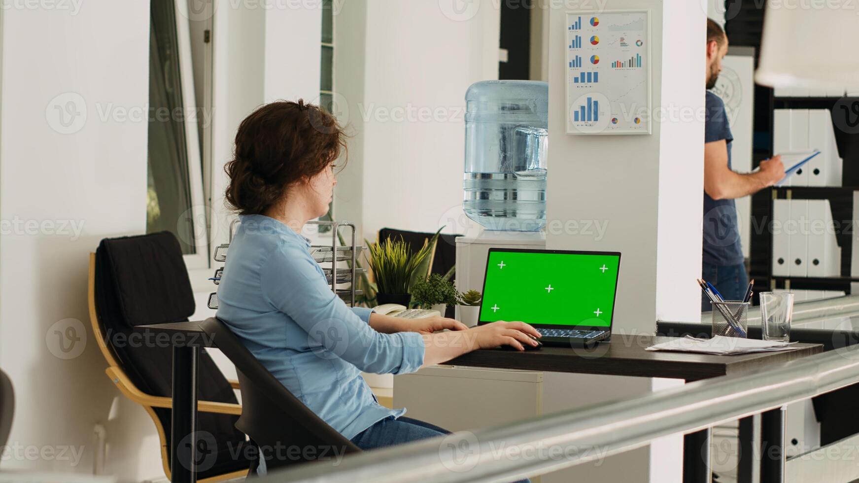 Office employee watches greenscreen on laptop display, working on small business operations at desk. Person looking at screen running isolated chromakey template with mockup copyspace. photo